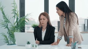 Video of successful business women standing around laptop for presentation of work in a modern startup.