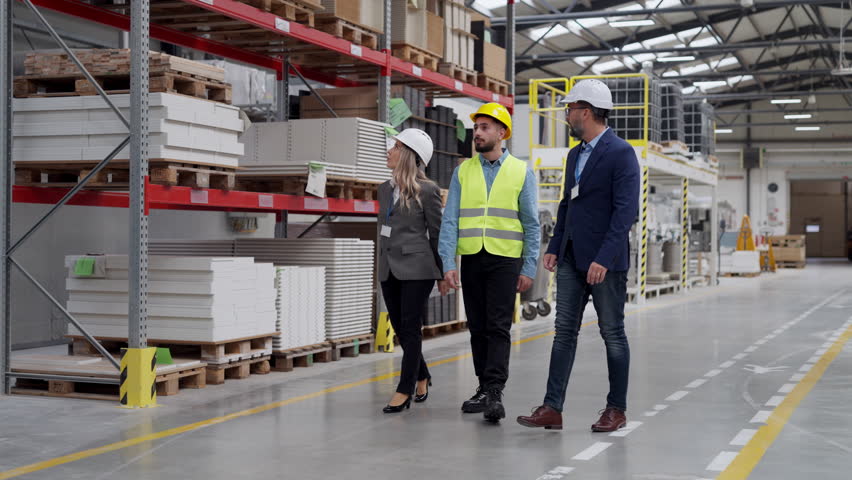 Engineers consulting with director in modern industrial factory, talking about new production project or investment. Team management in manufacturing facility.