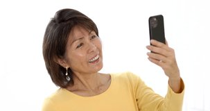 Closeup happy attractive woman smiling enjoying looking at mobile phone laughing talking using face time video chat closeup. Mature asian cheerful communicating on cellular smartphone studio lighting
