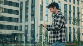 Side view happy Caucasian man casual walking street near modern buildings in city male businessman smiling guy looking at mobile phone smartphone texting message browsing social network walk outdoors - Powered by Shutterstock - Get 15% off with code: PIKWIZARD15