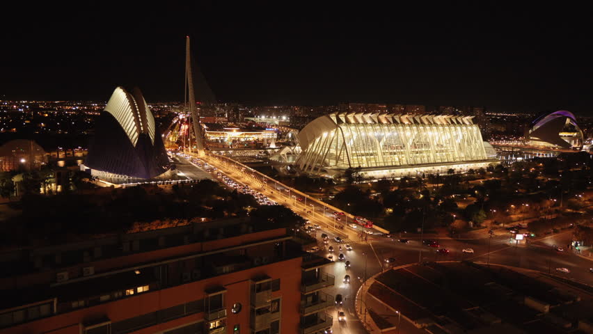 Aerial night view of Valencia City, with buildings illuminated against the dark sky, streets bustling with activity. Slow Motion, Camera 4K RAW. 