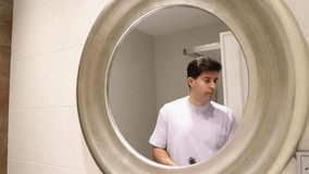 Caucasian man in t-shirt combing his hair reflected in the mirror 4k video footage clip closeup caucasian man