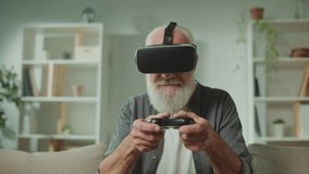 An Old Man in VR Glasses Plays Computer Games With a Joystick, Sitting in the Sofa and Eating a Popcorn.A Modern Elderly Man Plays PlayStation. Augmented Reality and Gaming for Seniors. - Powered by Shutterstock - Get 15% off with code: PIKWIZARD15