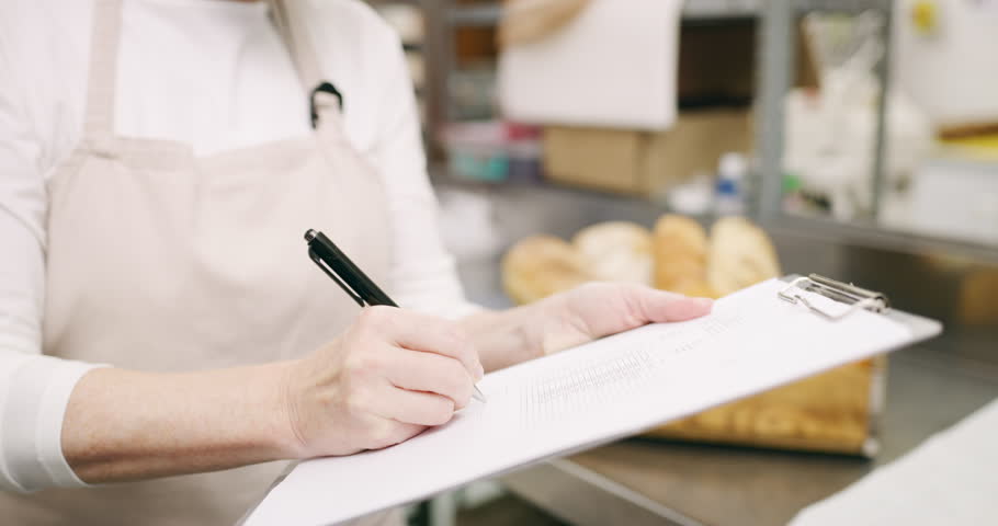 Hands, bakery and people with contract in restaurant catering with paperwork, list or clipboard. Pastries supply chain, small business closeup or chef with food, bread or notes for cooking in kitchen