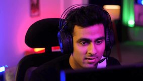 Indian man wearing headphones playing and enjoying a video game - gamer at home, virtual game, online video game. A young Asian handsome pro gamer - happy gamer after winning a game,