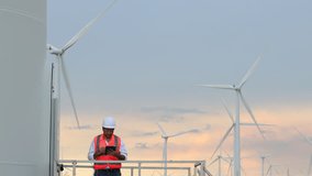 Asian engineers in hardhats and safety vests interacting with the tablet, analyzing data while standing near the wind turbine, monitoring its performance and maintenance data. - Powered by Shutterstock - Get 15% off with code: PIKWIZARD15