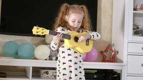 4K Video : Little child playing ukulele in front of sofa