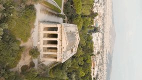 Vertical video. Athens, Greece. Temple of Hephaestus. Athenian Agora in the light of the morning sun. Summer, Aerial View, Departure of the camera