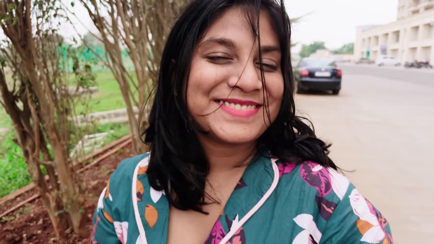 Portrait of a young smiling woman looking relax outdoors with a blurred street background