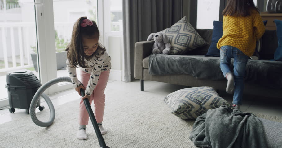 Girls, children cleaning and vacuum carpet in living room, hygiene and housekeeping in home. Electrical appliance, kids and housework on floor for chores of sisters together to help dust apartment