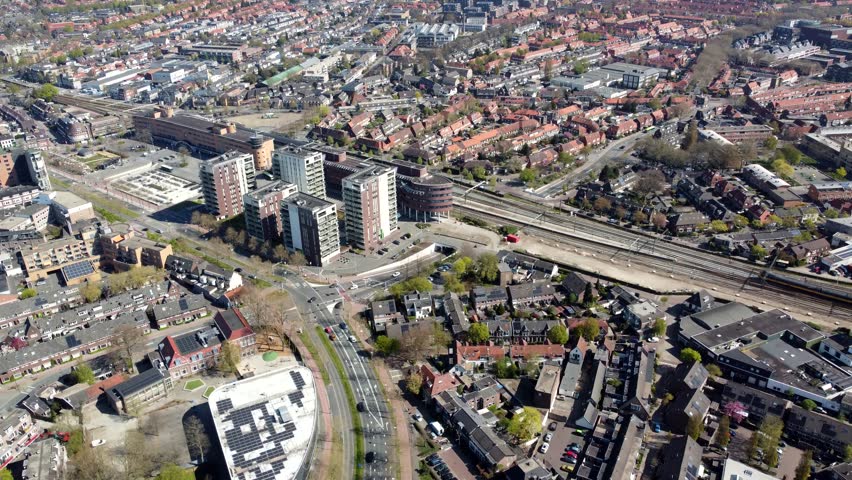 Aerial drone view arriving at Hilversum railway station showing train arrived and people onboarding in the background building and the surrounding office buildings used by companies 4k resolution Royalty-Free Stock Footage #3420872621