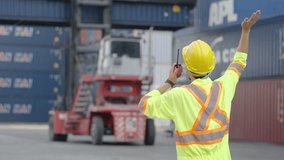Asian foreman in hardhat and safety vest talking on the walkie-talkie control loading Containers box at warehouse logistic in Cargo freight ship for import export in harbor, shipping loading in docks - Powered by Shutterstock - Get 15% off with code: PIKWIZARD15