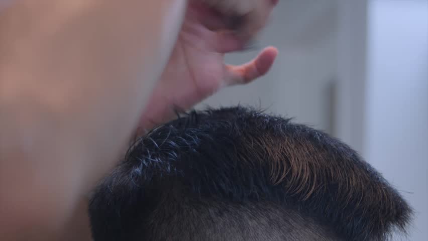 Smooth black hair on top of head being measured by hand and comb then cut by scissors, filmed as closeup shot in handheld style on right side of head Royalty-Free Stock Footage #3420896513