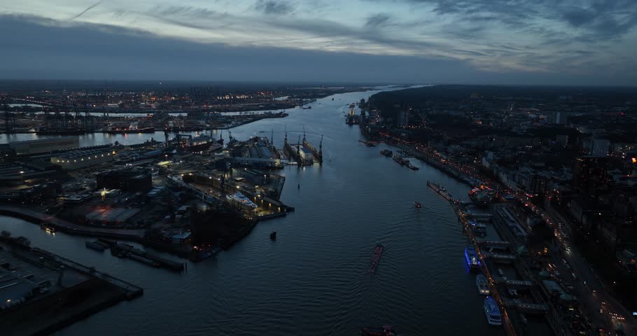 Urban city view of Hamburg, one side the large industrial commercial port and on the other side the city at dusk.Large city in Germany, city skyline and river Elbe.