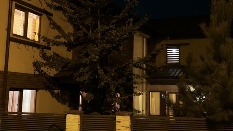 Establishing shot of smart residential house with lights turning on and off on first and second floor
