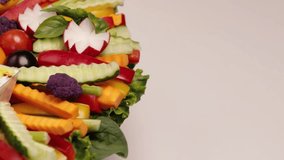 Sliced raw vegetables on a plate with hummus and white sauce. Vegetarian healthy food. A colorful arrangement for a buffet. Top view. Video looped