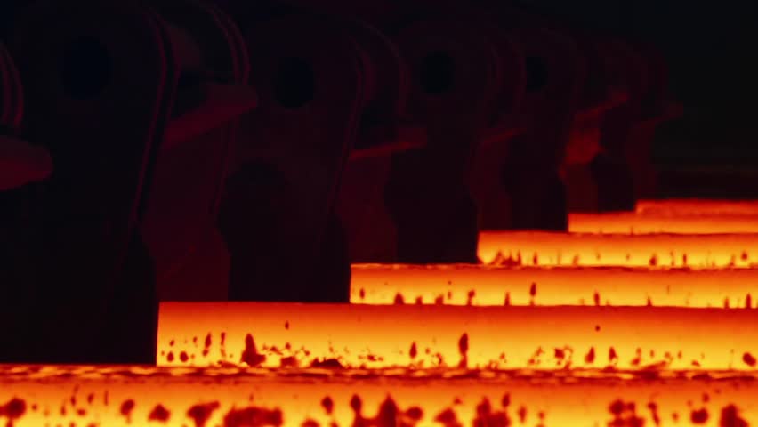 Hot metal sheet slides along the conveyor. Heavy industry. Red hot steel metal billets after molten steel casting. Hot steel bars on the conveyor.