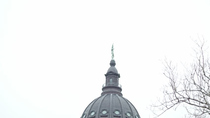 Kansas state capitol building with flags waving in Topeka, Kansas with medium shot video tilting down.