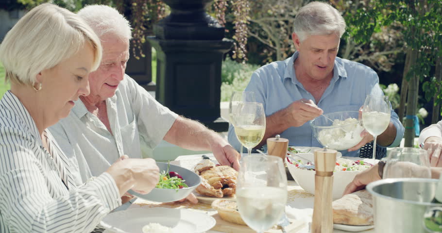 Eating lunch, senior friends and talk at table, party and celebration in outdoor garden at home. Food, wine and group of people in retirement together at social gathering with alcohol glass or salad