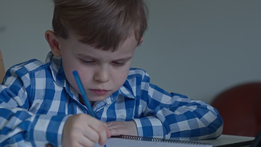 A bored tired sad upset little child boy kid son schoolboy schoolchild student at the table desk writing homework boring class lesson drawing Royalty-Free Stock Footage #3421048781