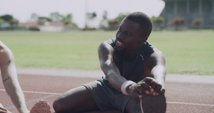 Happy group, stretching and fitness in running, exercise or getting ready for sport on outdoor stadium track. People, friends or athletes in warm up or leg stretch for preparation, race or sprint