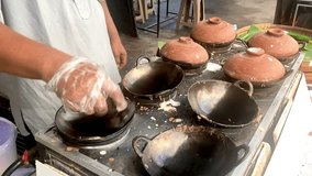 A man cook traditional Javanese pancake called Serabi using wok pan and clay pot as lid