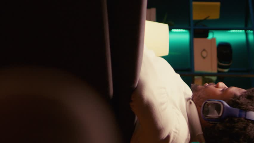 Vertical video Man plays SF singleplayer game with overlay HUD showing health bars and minimap on widescreen TV. Gamer enjoying high quality ray tracing graphics in console videogame, panning shot