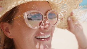 Close up face of young sunshine woman in straw hat look at ocean beach reflecting in mirror sunglasses. Smiling beautiful lady portrait feeling happy outdoor on summer holidays. Slow motion travel 4K - Powered by Shutterstock - Get 15% off with code: PIKWIZARD15