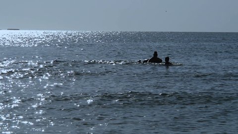 A woman with a child on an inflatable circle is swimming in the sea.