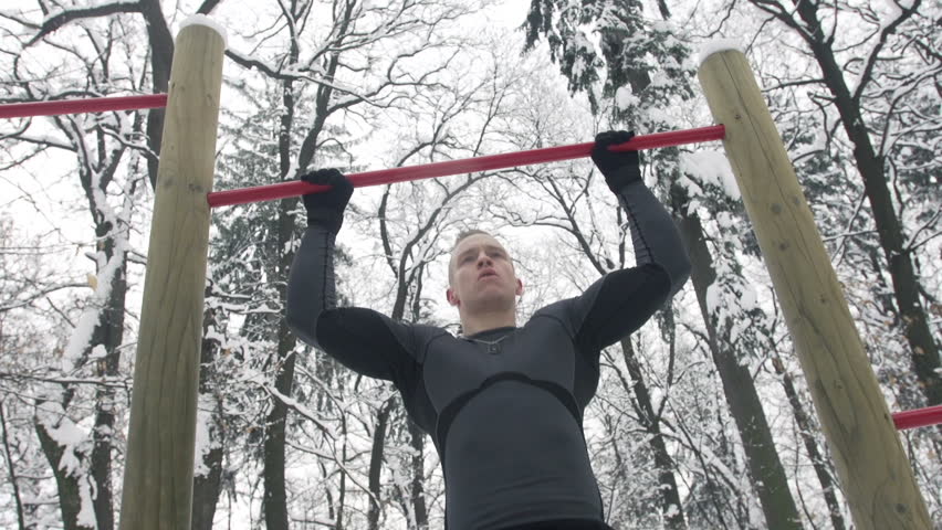 Slow Motion Of Young Sportsman Doing Pull-Ups Outdoors In Snow 