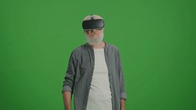 Green Screen. An Old Man With Gray Beard in VR Glasses Examines and Touches Everything Around. Virtual Reality Education for the Elderly. - Powered by Shutterstock - Get 15% off with code: PIKWIZARD15