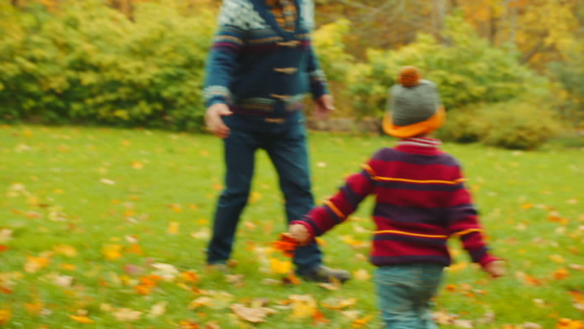 Grandfather is playing catch-up with his grandchildren in the autumn park Royalty-Free Stock Footage #34214410