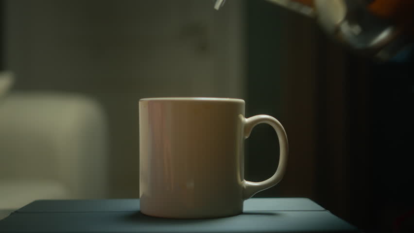 Close-up of hot water pouring from a teapot into a white cup