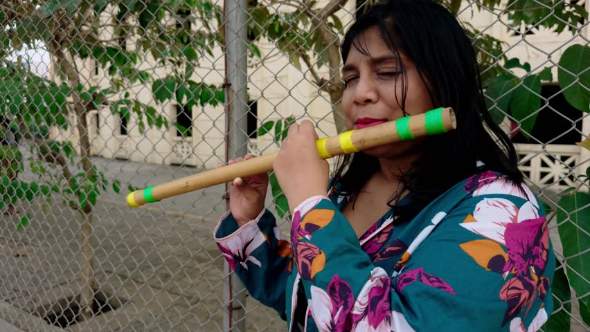 Woman playing traditional wooden flute outdoors with a focus on cultural music expression asian fatty girl