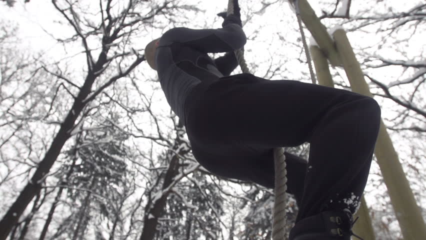 Slow Motion Of Young Muscular Sportsman Climbing Up The Rope Outdoors
