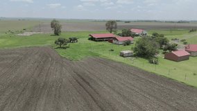 Aerial 4k footage of a farm house with farming equipment, a high speed sprayer for crops, driving around the farm.