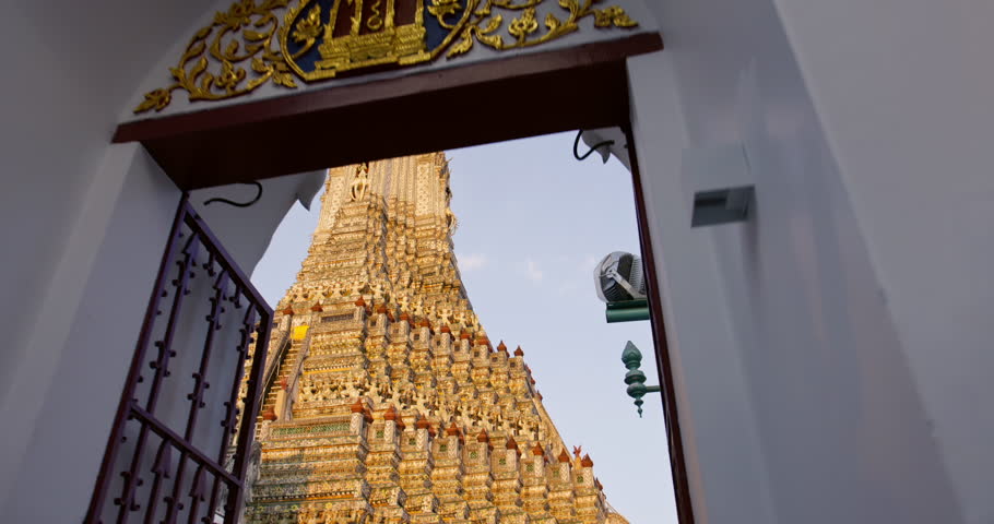 Tilt slide motion through entrance reveal Wat Arun Temple of Dawn in sunset glow