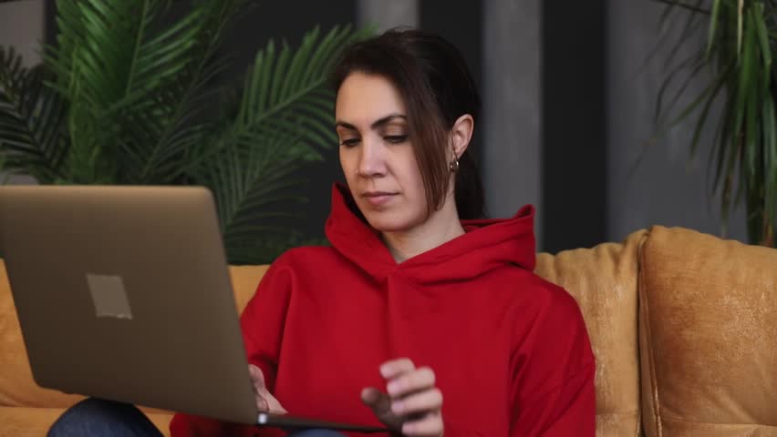 Happy young woman sits in the living room with a laptop and talks on it online remotely. Concept of long distance relationship or online communication Royalty-Free Stock Footage #3421672987