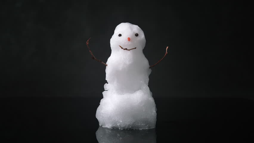 Snowman melting on black background. Real snowman melts quickly. Timelapse 4k video.