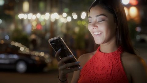 A young, beautiful hispanic woman use phone.Sends  voice message and chat while smiling. street cars and people beautifull background apps for young adults friendship technology advantages