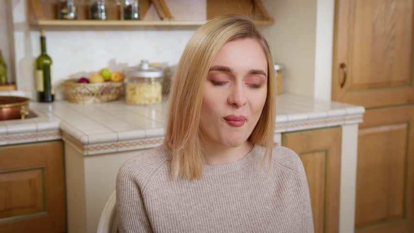 Young pretty blonde woman is chewing savoring food. The emotion of satisfaction.