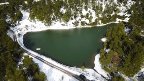 Aerial drone bird's eye view video of famous heart shaped lake Beletsi covered with snow, Ipokrateios politeia, Parnitha, Attica, Greece  