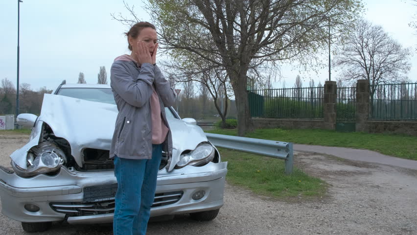 Confussion by smashed car. A view of urban street with confussed woman stand by the crashed car in the day light.