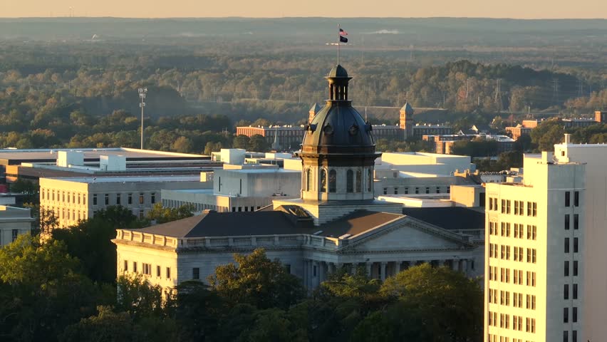 Dawn light on the South Carolina State House dome with the flag above. Aerial parallax during sunrise.