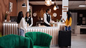 Asian women approach front desk to ask about their room, arriving at hotel from the airport and hoping for an early check in. Reception staff team greeting travelers and ensuring pleasant stay. - Powered by Shutterstock - Get 15% off with code: PIKWIZARD15