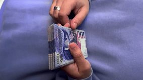 4K vertical video. Woman in purple sweatshirt counts lilac paper banknotes Georgian 100 lari. Concept of currency exchange, immigration to Georgia, travel, tourism, trip, credit. Cash to pay. Money