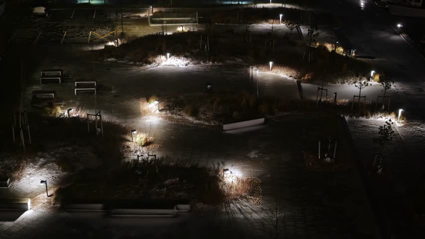 The small park is illuminated, and at night, when there is a strong wind, there is not a single person in the park.