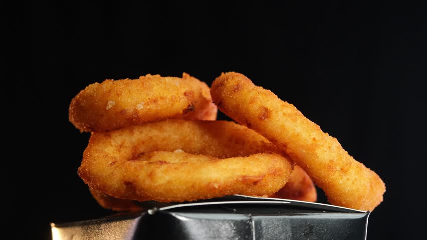 Fried crispy onion rings in a frying pan with boiling oil top view. Roasted onion rings for snacks at bar, cafe. Fast food. Delivery. Beer snacks
