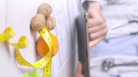 Vertical video, diet specialist using a table during a dieting appointment, Walnuts and Tangerine on desk