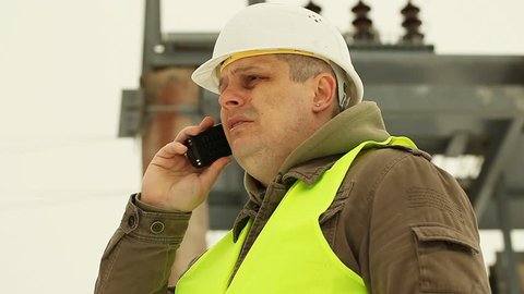 Engineer with cell phone on a transformer background 
